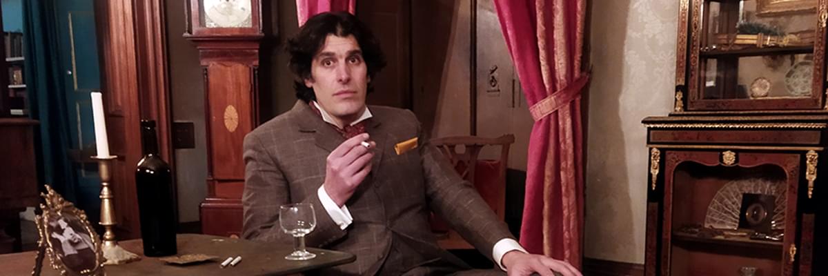 Actor Will Govan sits in a luxurious surroundings, dressed as Irish poet, Oscar Wilde.