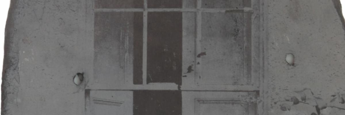 Image of etched slate print of old looking house, close up of window and brick work in grey scale.